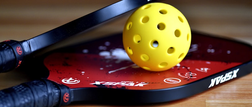 a yellow tennis ball sitting on top of a racket