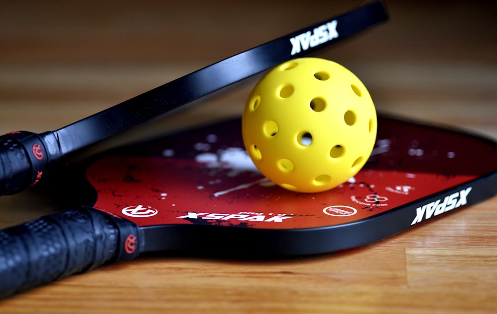 a yellow tennis ball sitting on top of a racket