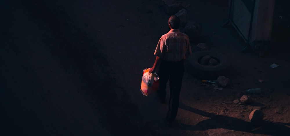 a man standing in the dark holding a bag