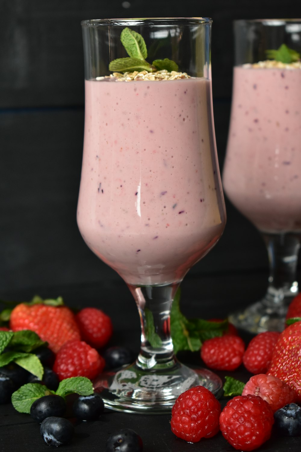 two glasses filled with a smoothie and berries