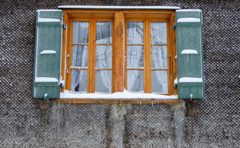a window with a curtain and snow on the window sill