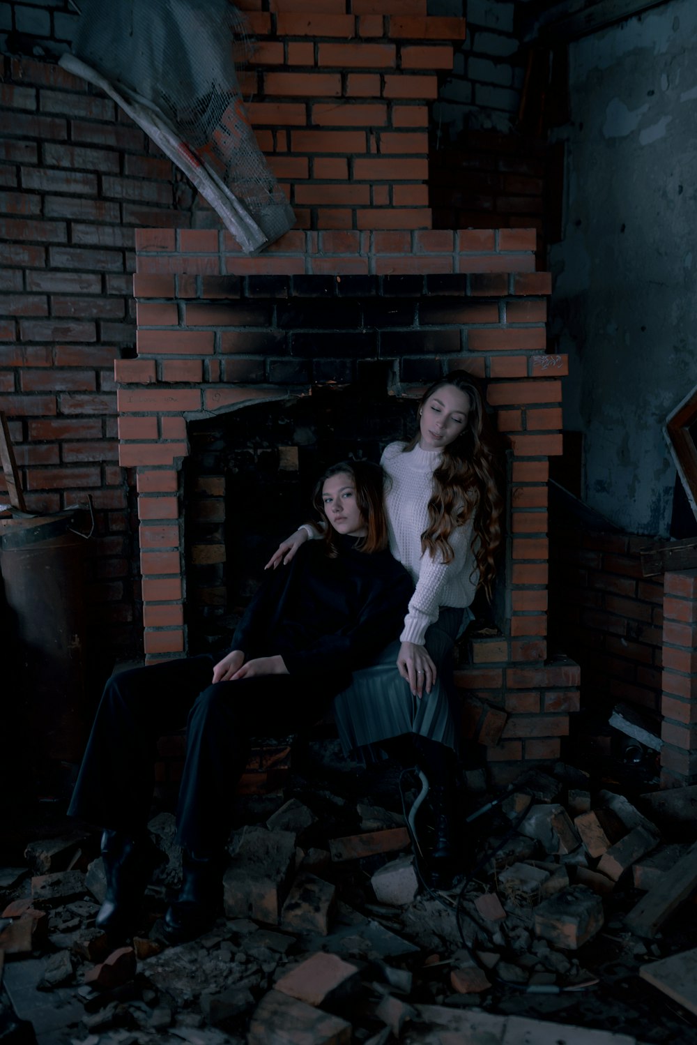 two women sitting on a chair in front of a fire place