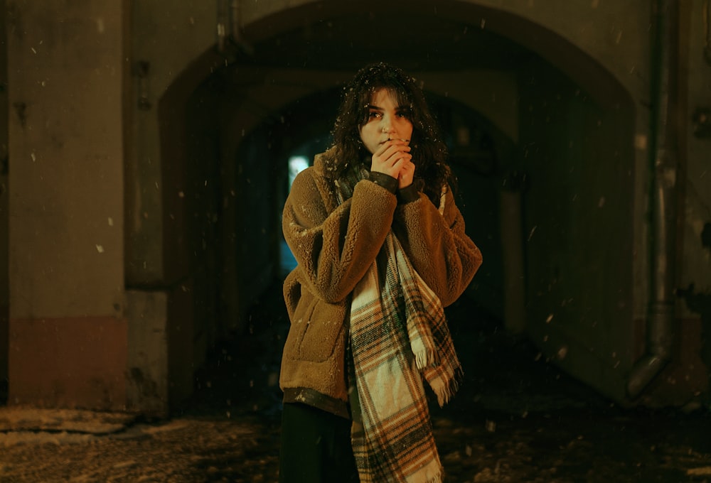 a woman standing in a tunnel with a scarf around her neck