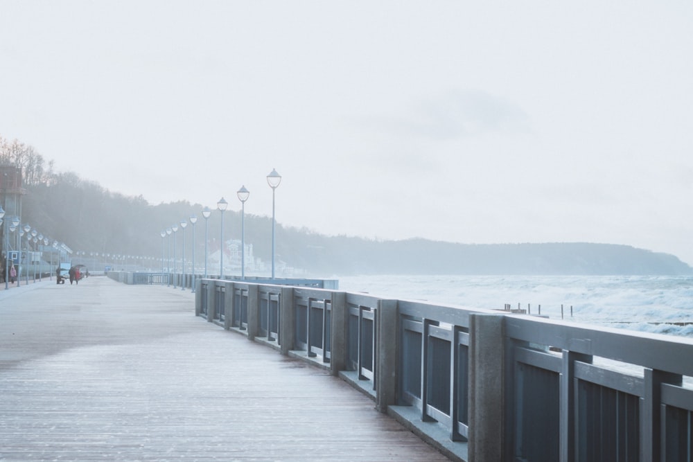 a boardwalk next to the ocean on a foggy day