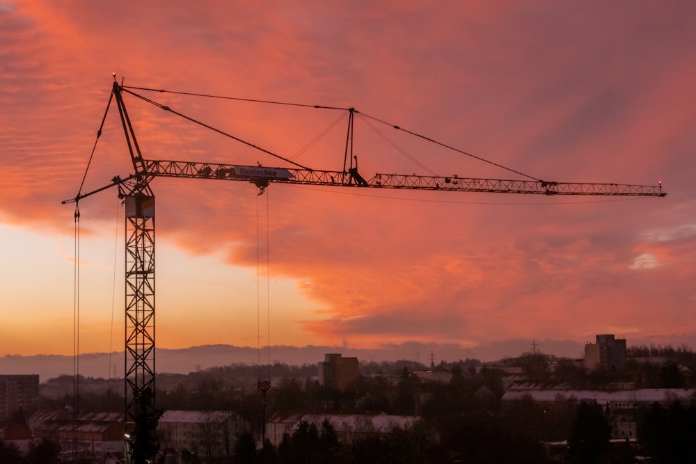 a crane is silhouetted against a sunset sky