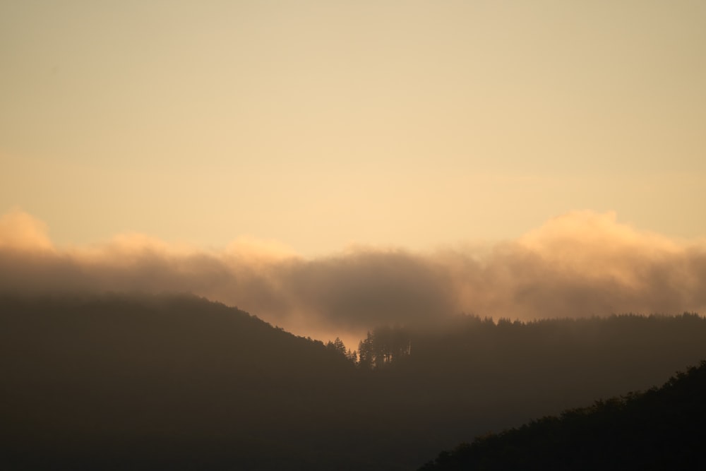 the sun is shining through the clouds over the mountains