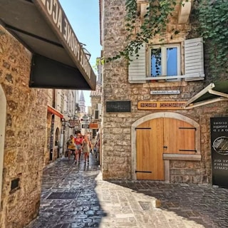 Ancient cobblestone alleyway lined with ivy-covered stone houses in a quaint village