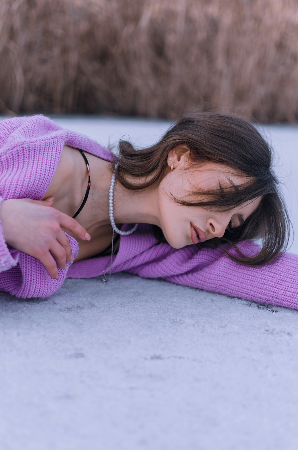 a woman laying on the ground in a purple sweater