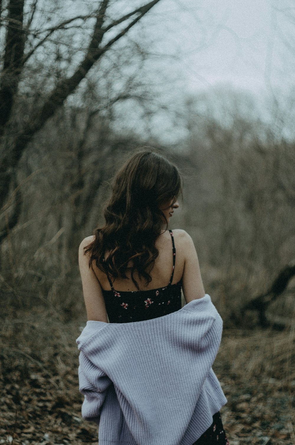 a woman in a black and white dress walking through a forest