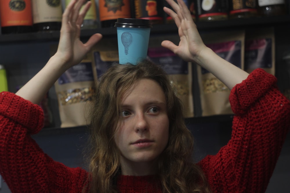 a woman holding a coffee cup above her head