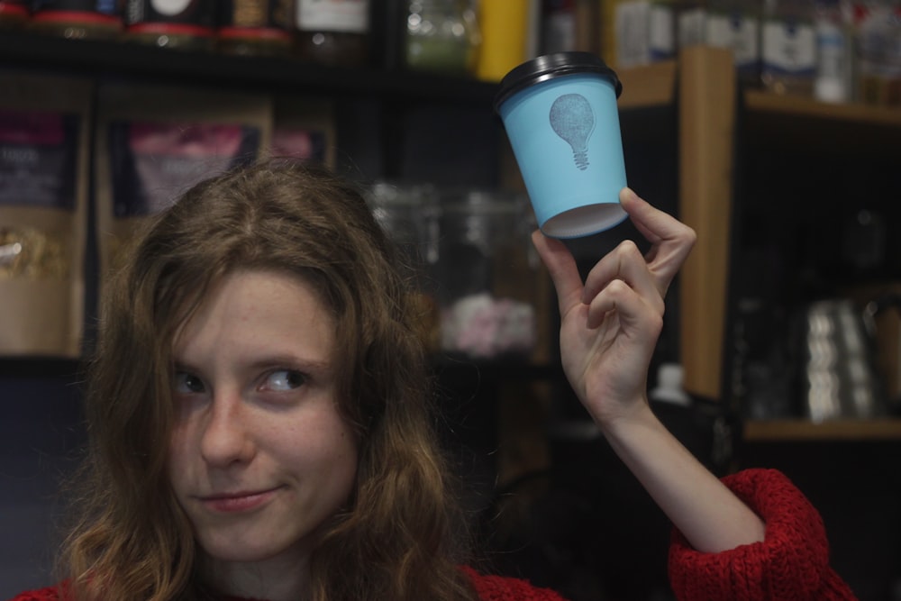 a woman holding up a cup with a light bulb on it