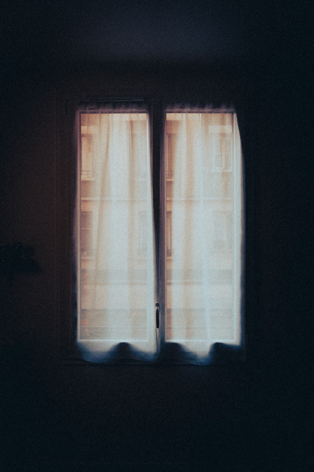 a dark room with two windows and a curtain