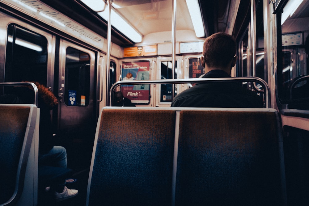 a man is sitting on a train looking out the window