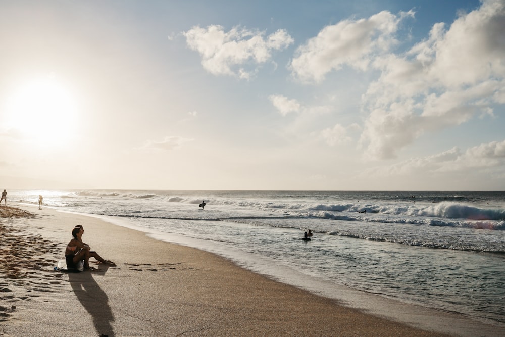 a person sitting on a beach next to the ocean