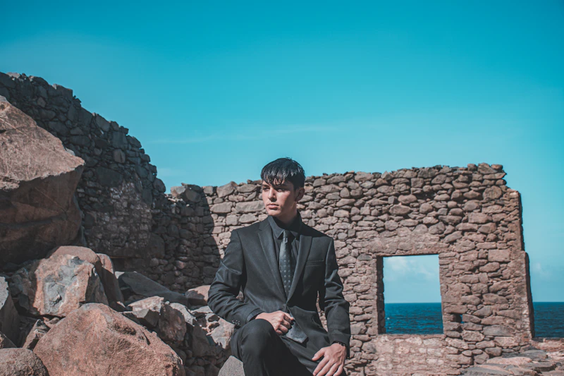 a man in a suit sitting on a rock