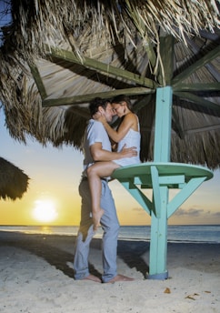 a man and a woman embracing under an umbrella on the beach
