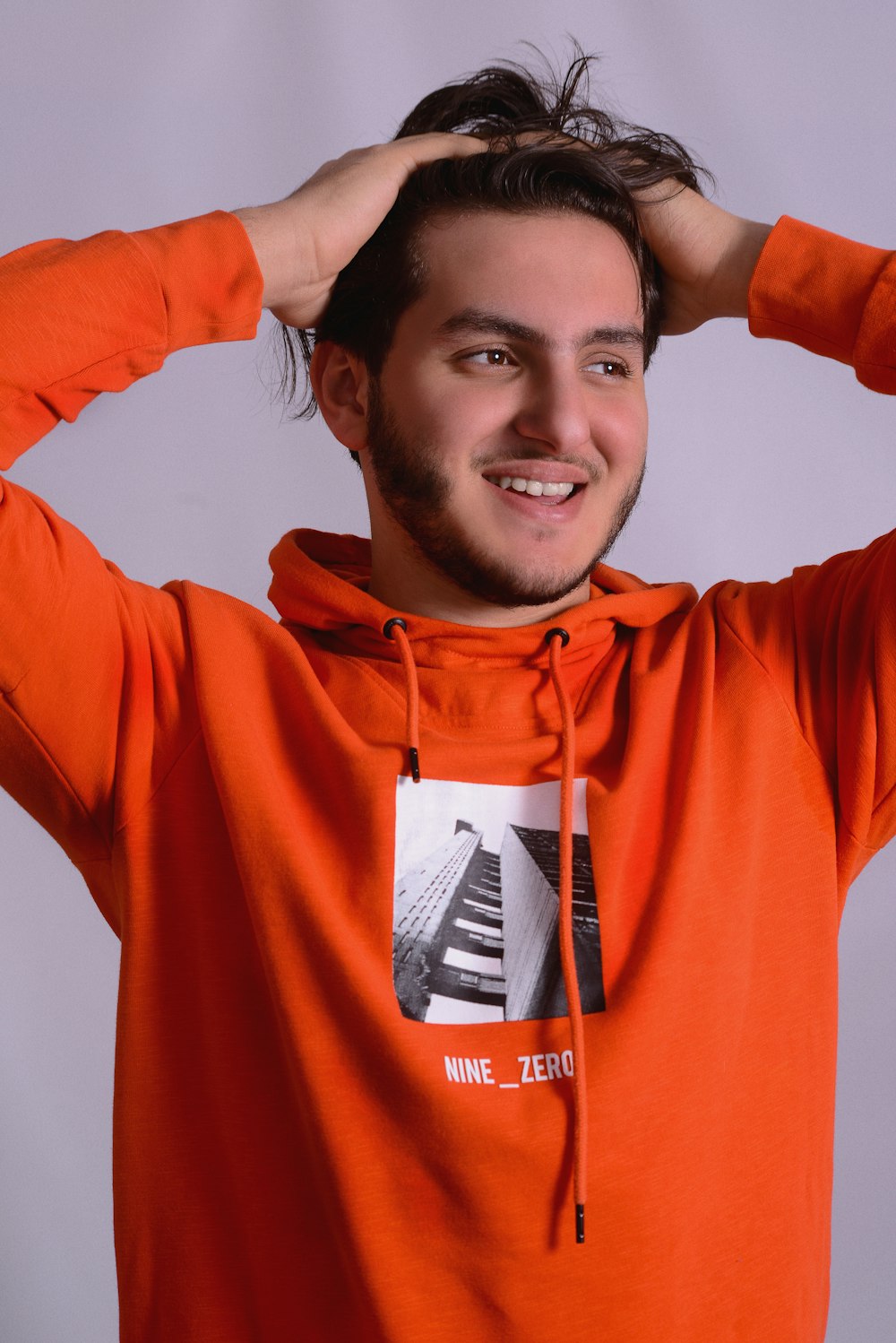 a man in an orange hoodie is posing for a picture