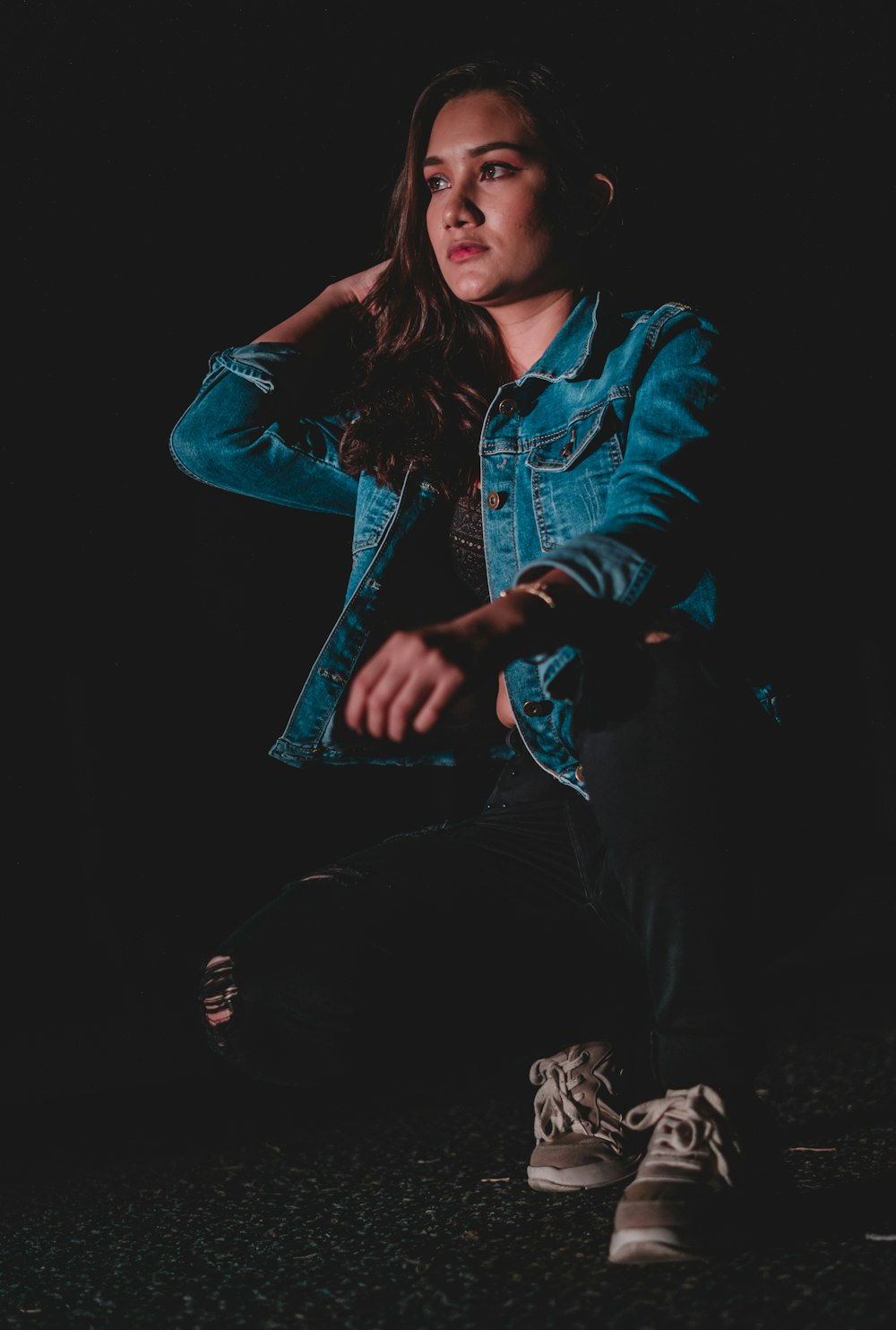 a woman sitting on the ground in a dark room