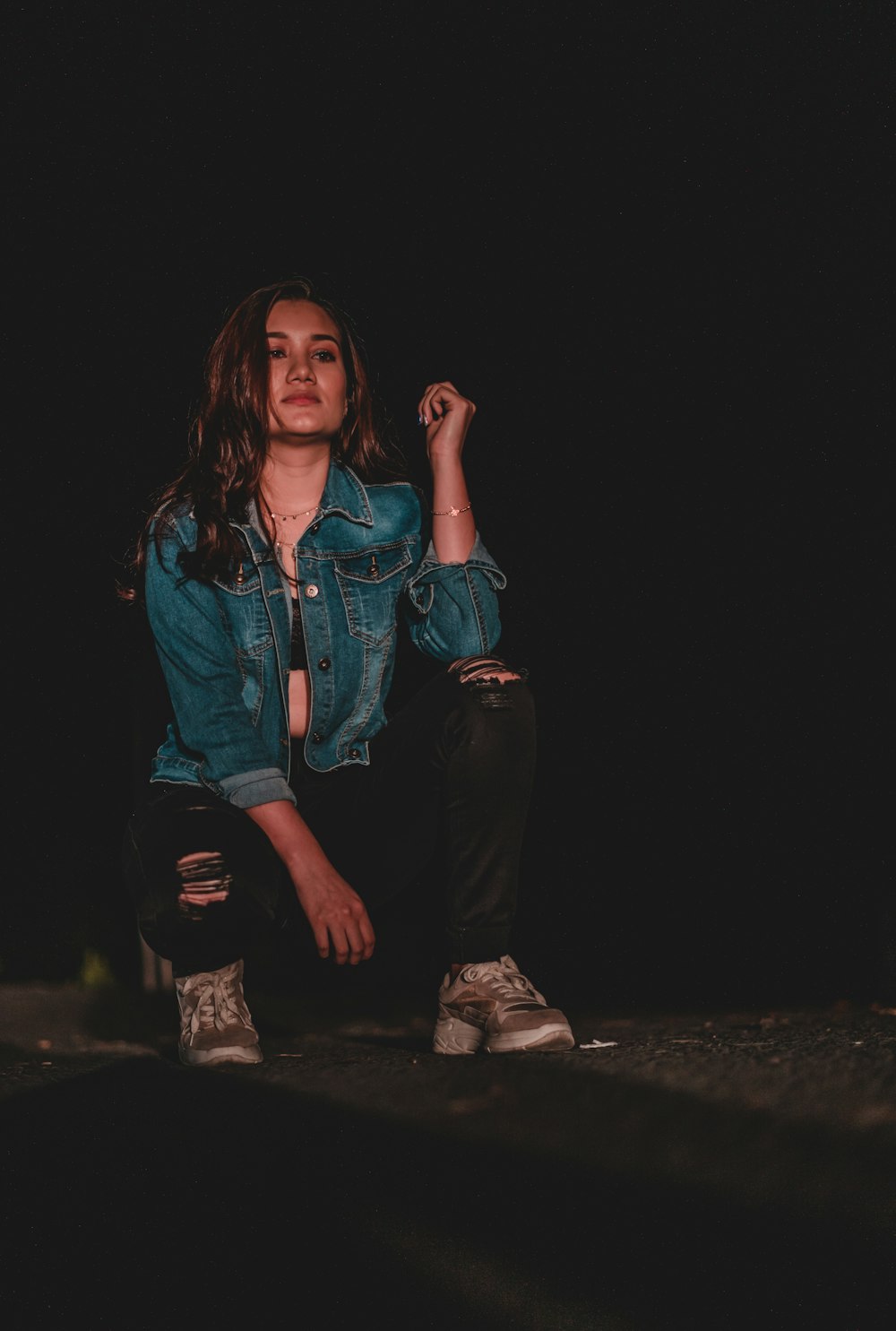 a woman sitting on the ground in a dark room