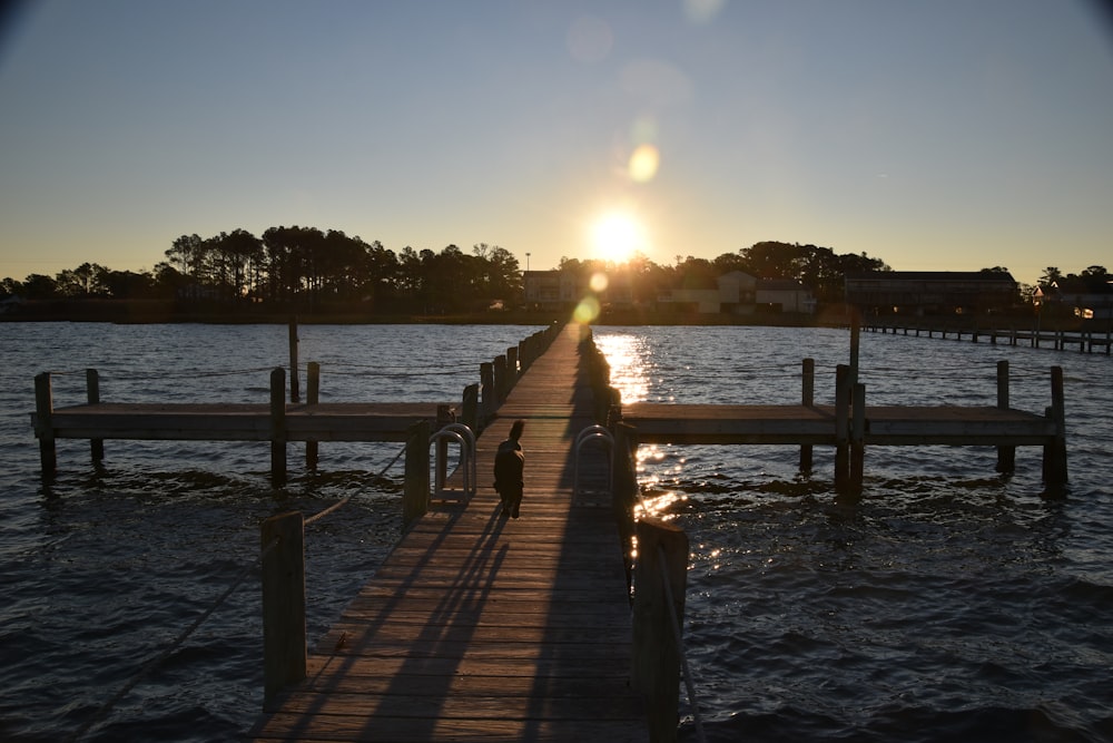 the sun is setting over the water at a dock