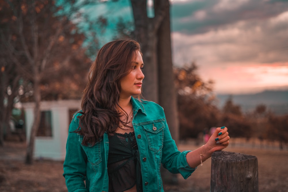 a woman standing next to a wooden post