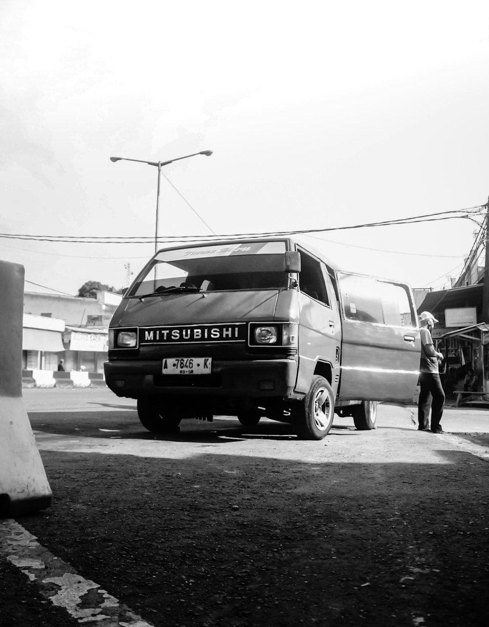 uma foto em preto e branco de um homem em pé ao lado de uma van