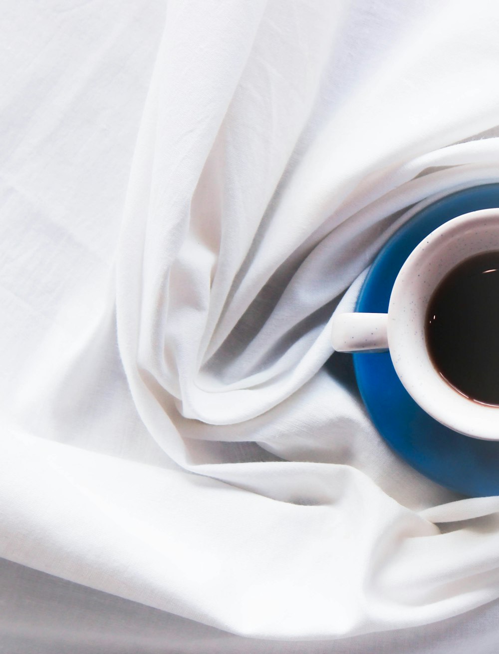 a cup of coffee sitting on top of a white cloth