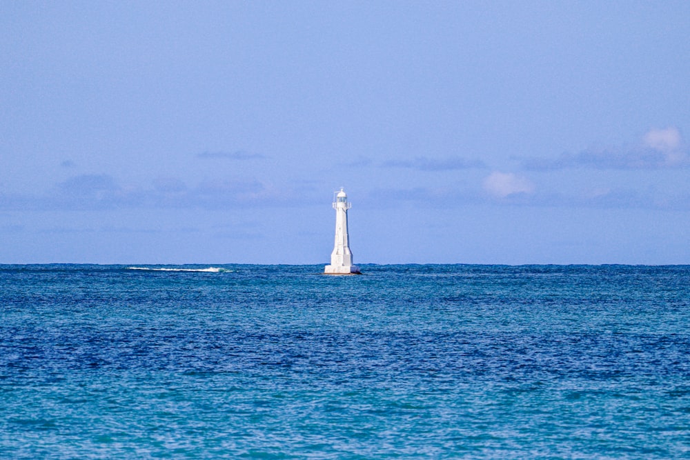 a white lighthouse in the middle of the ocean
