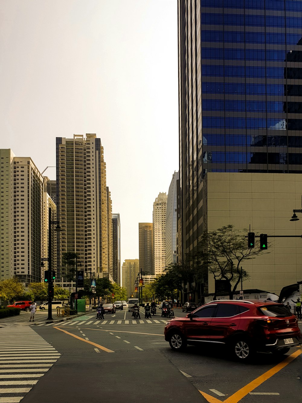 a red car driving down a street next to tall buildings