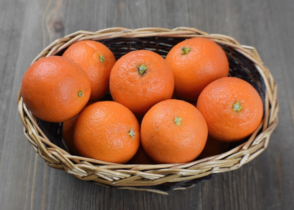 a basket filled with oranges on top of a wooden table