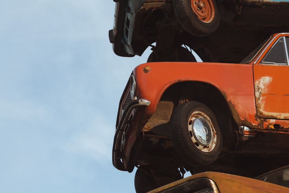 an old orange truck is stacked on top of another orange truck