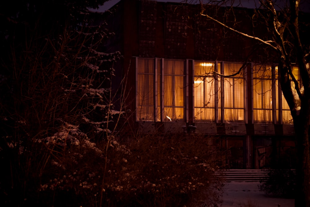 a house lit up at night with snow on the ground