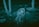 A person wearing a hooded jacket displays a frightened expression, pressing their hands against their face. The eyes appear unnaturally rolled back. The surroundings are dimly lit, with trees and rocks in the background, giving a creepy or horror-like atmosphere.