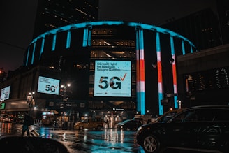 a city street at night with cars and billboards