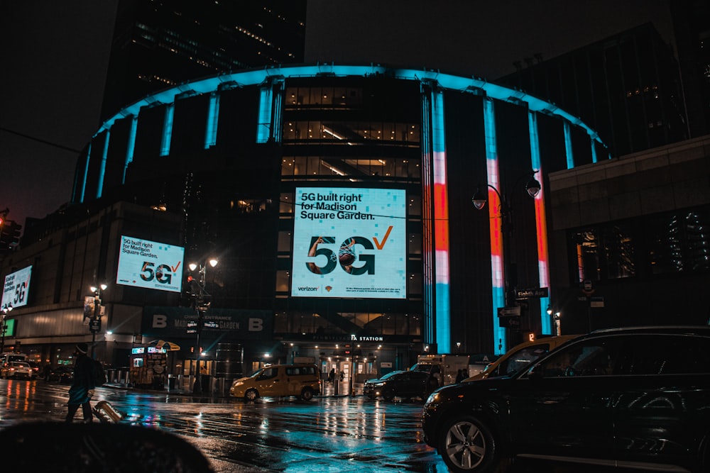 a city street at night with cars and billboards