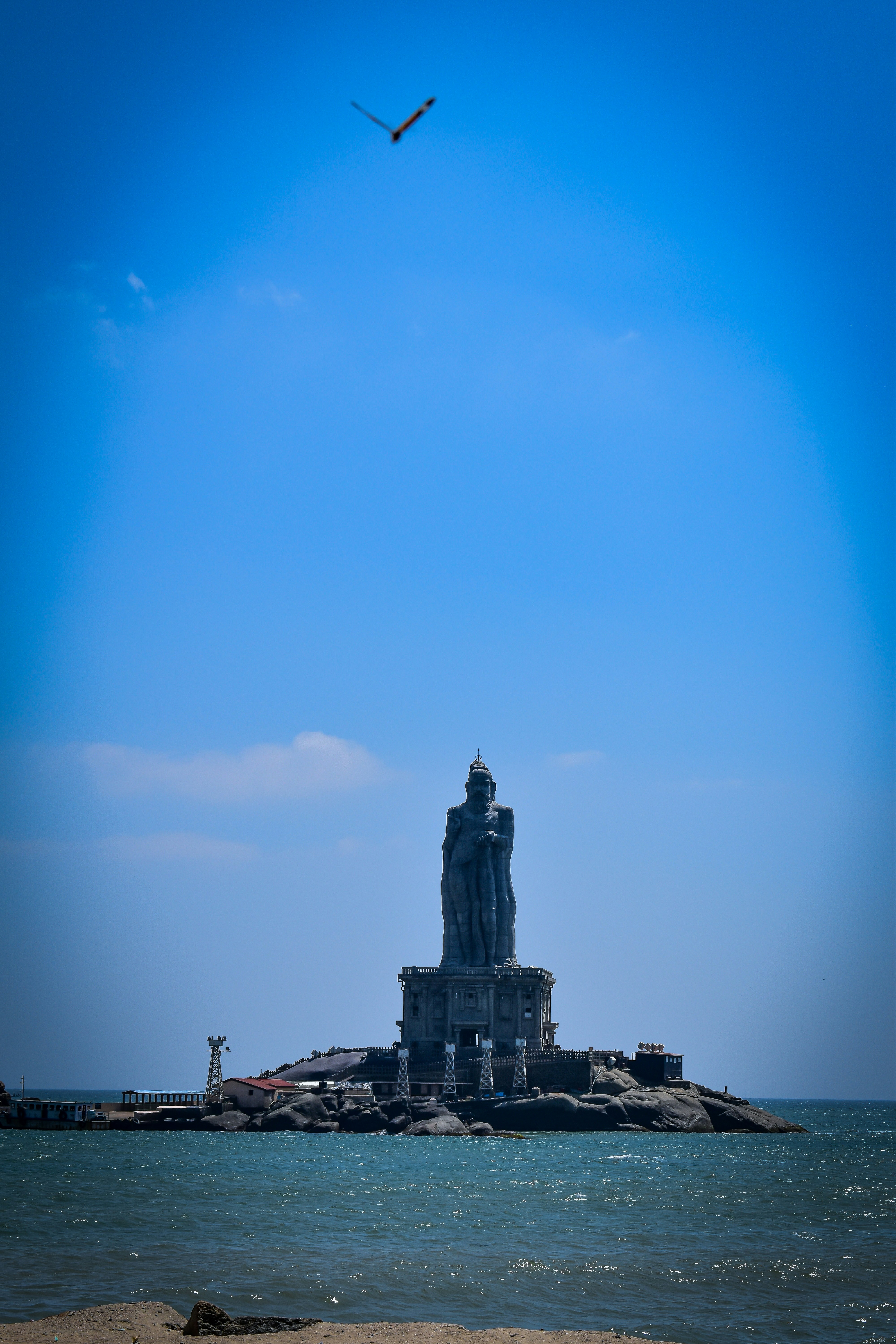 Ein Vogel fliegt über eine Statue mitten im Ozean