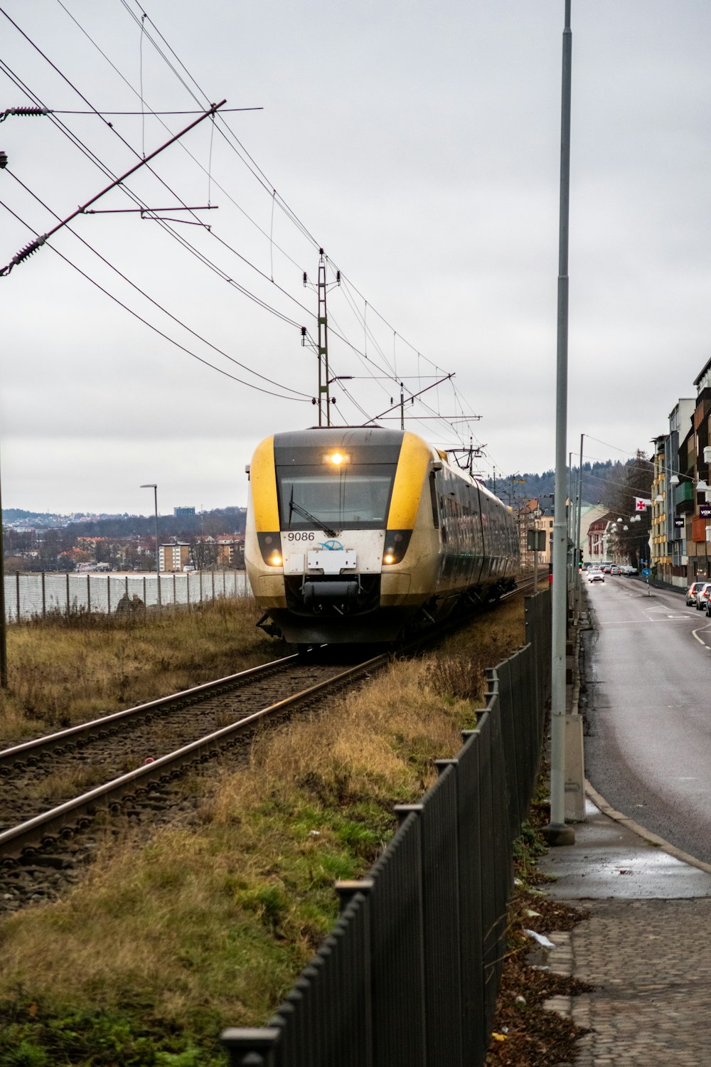 Un treno giallo e bianco che viaggia lungo i binari del treno