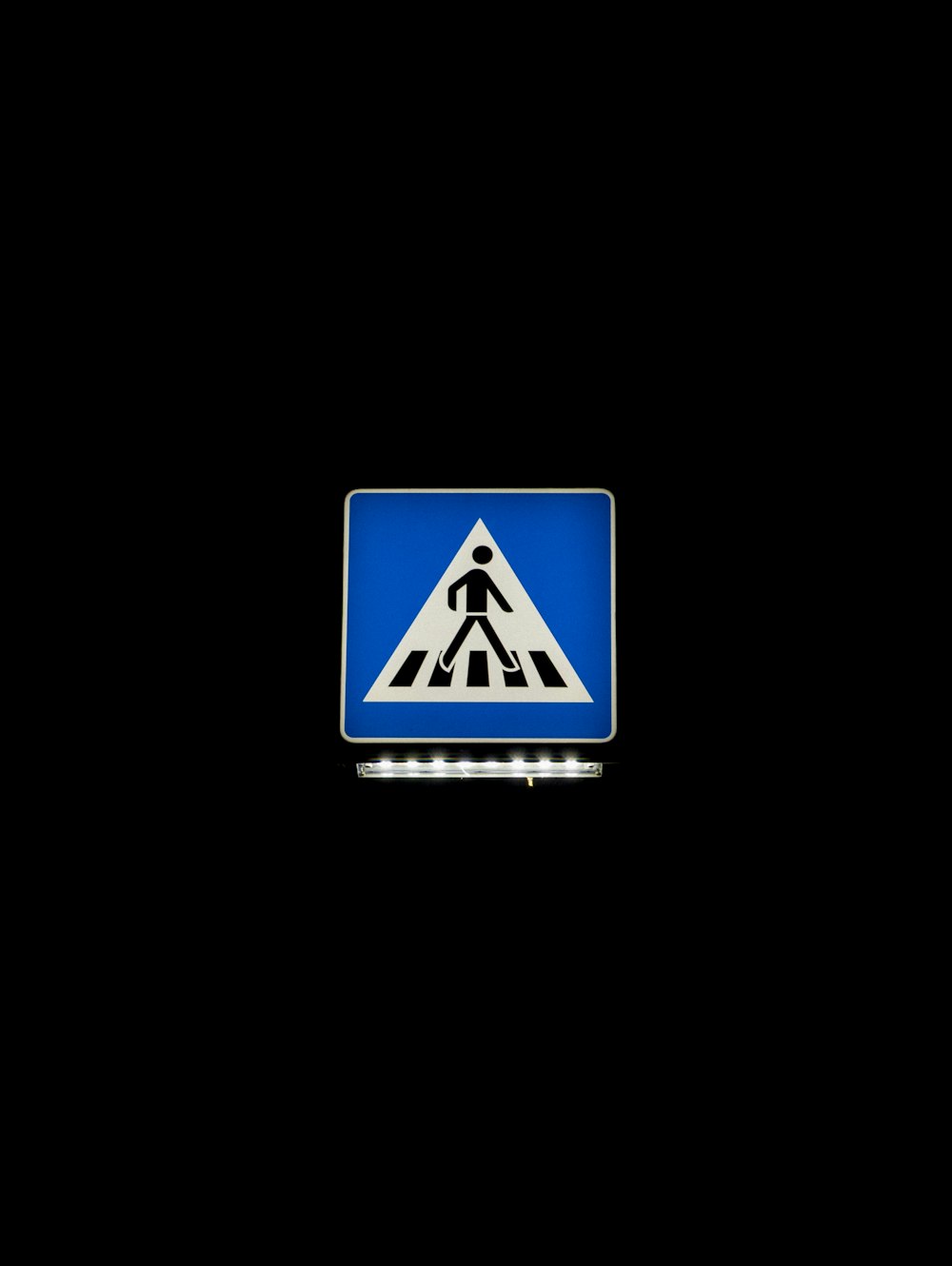 a blue pedestrian crossing sign on a black background