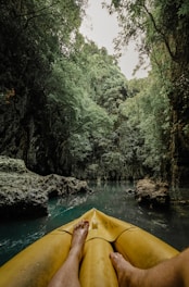 a person's feet on a yellow kayak in a river