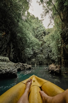 a person's feet on a yellow kayak in a river