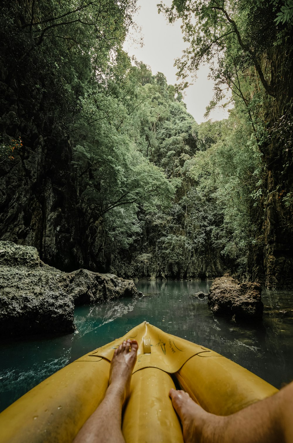 a person's feet on a yellow kayak in a river