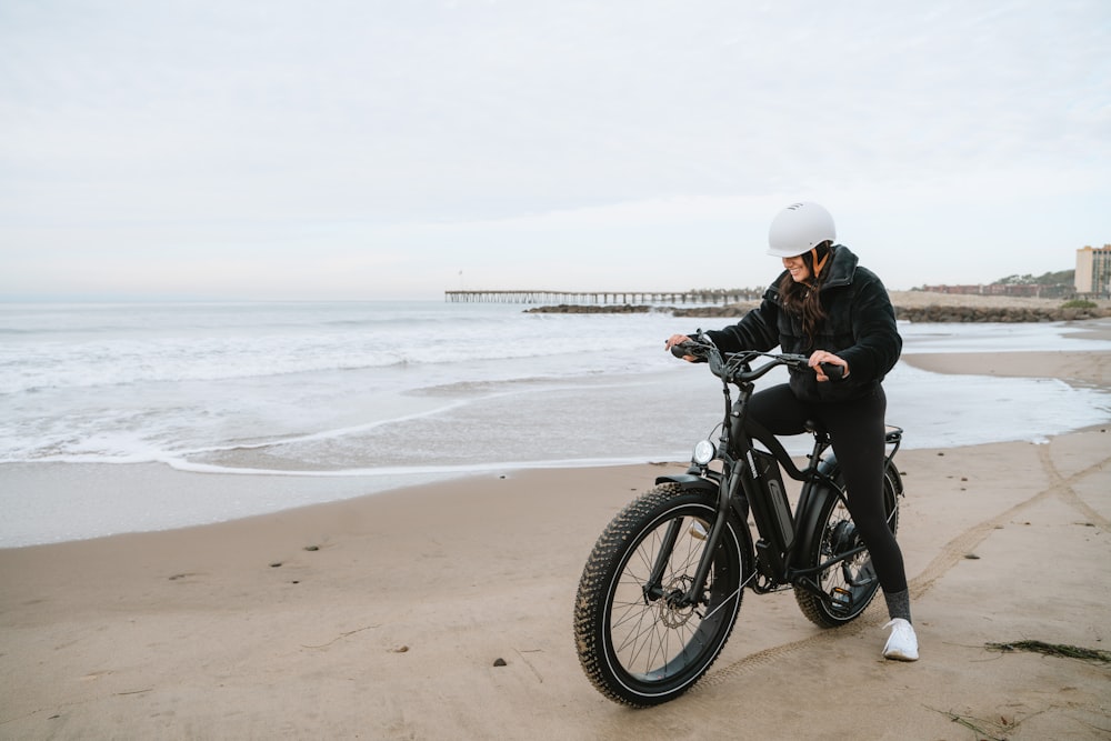 a woman sitting on a bike on the beach