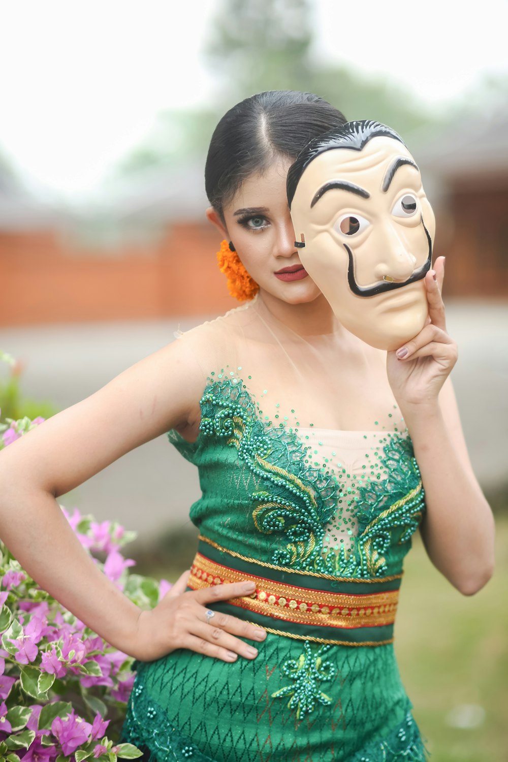 a woman in a green dress holding a mask