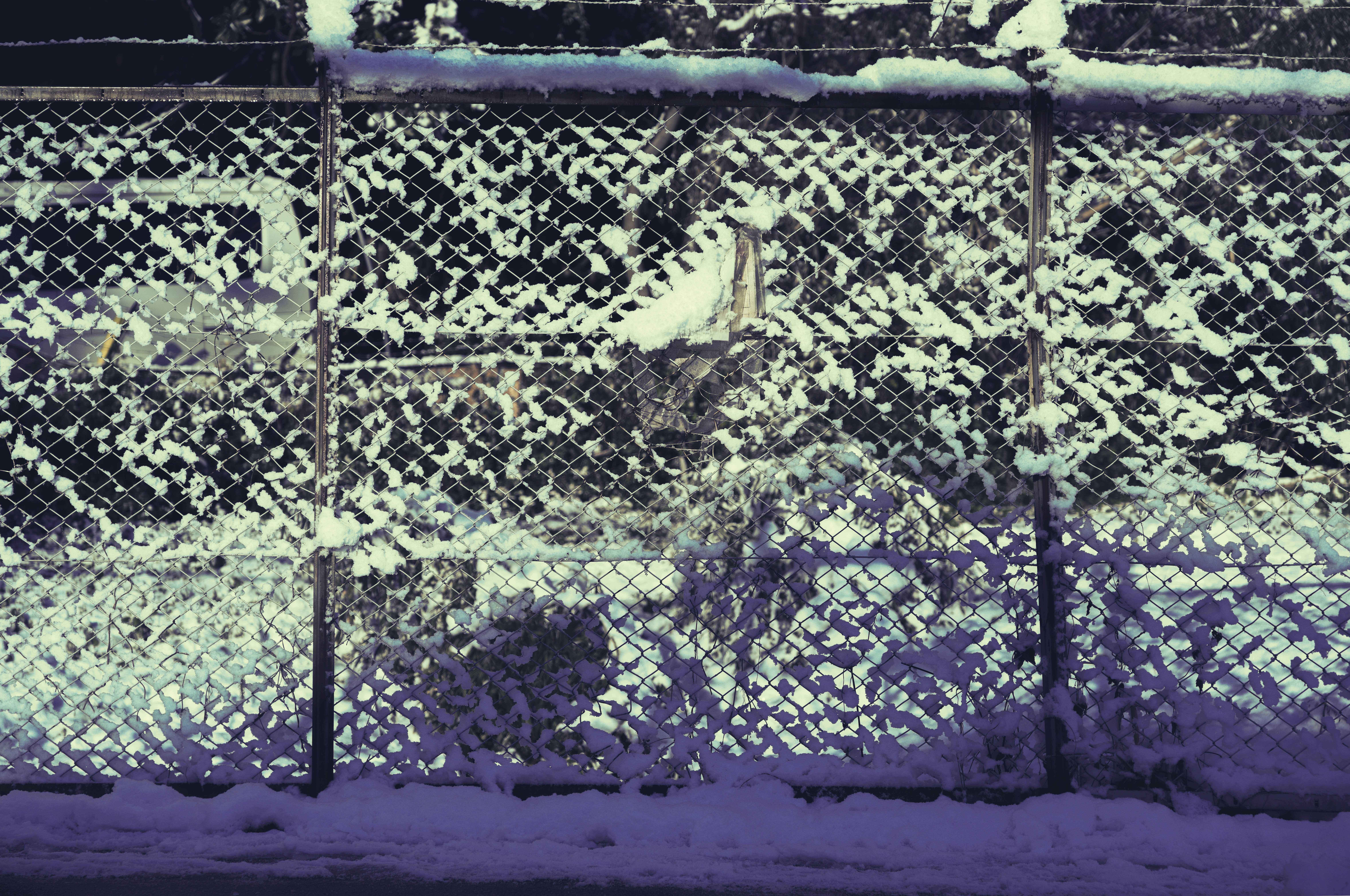 a fence covered in snow next to a street