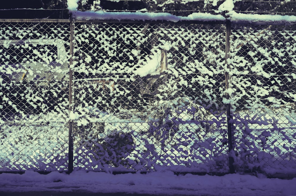 a fence covered in snow next to a street