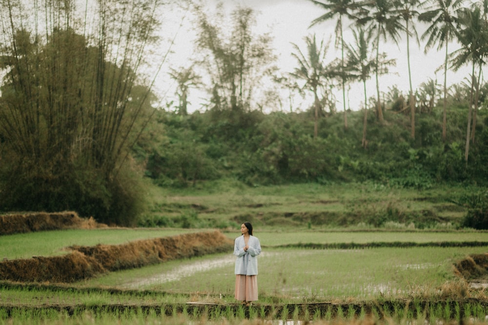 a woman standing in the middle of a rice field