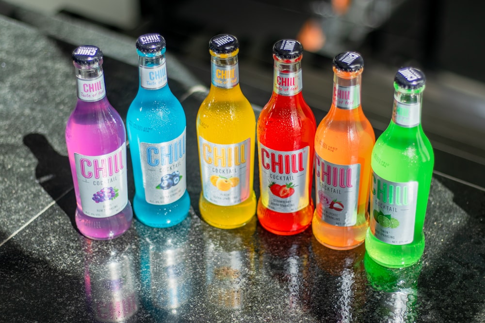 a group of bottles of different colored drinks