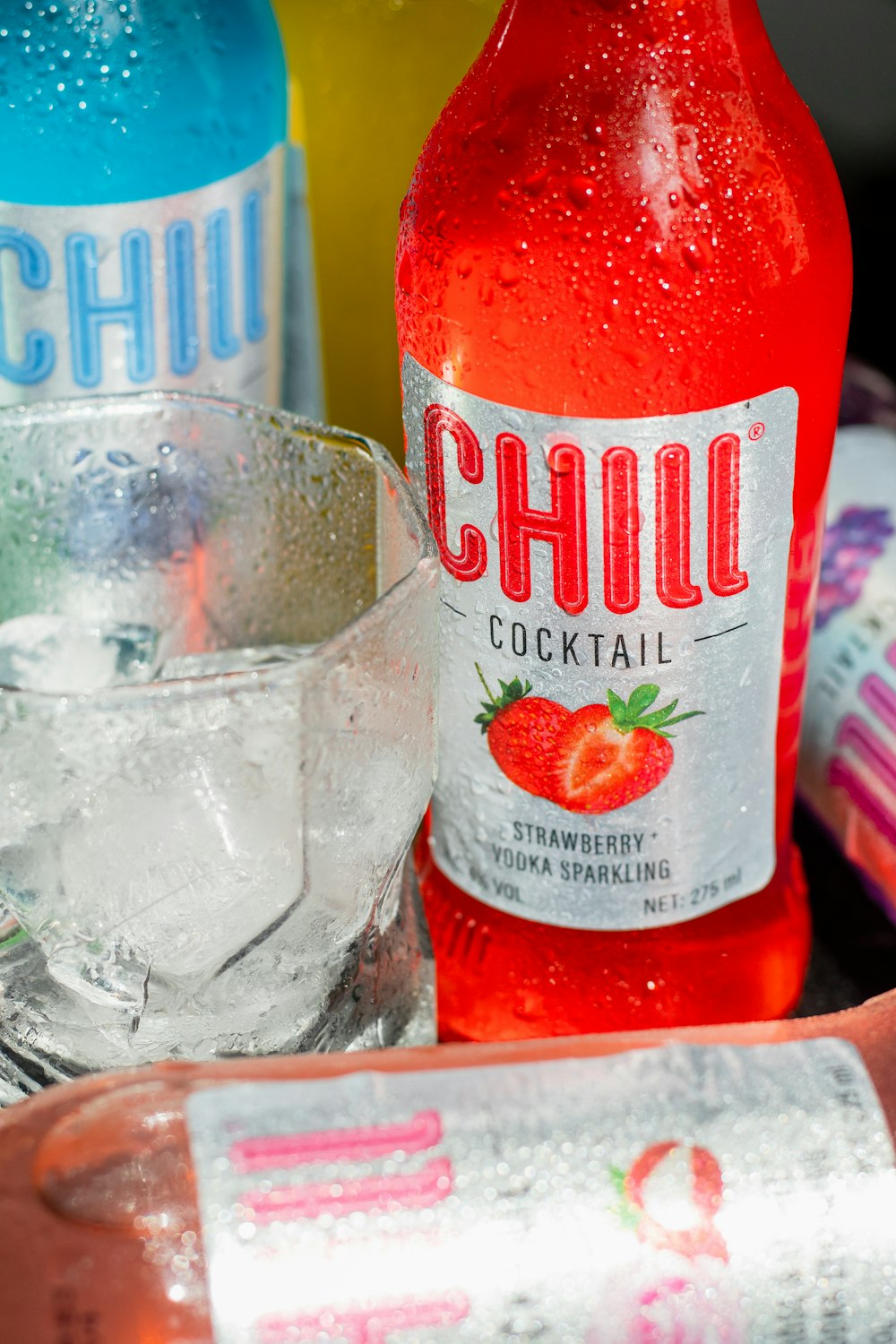 a close up of a bottle of soda next to a glass