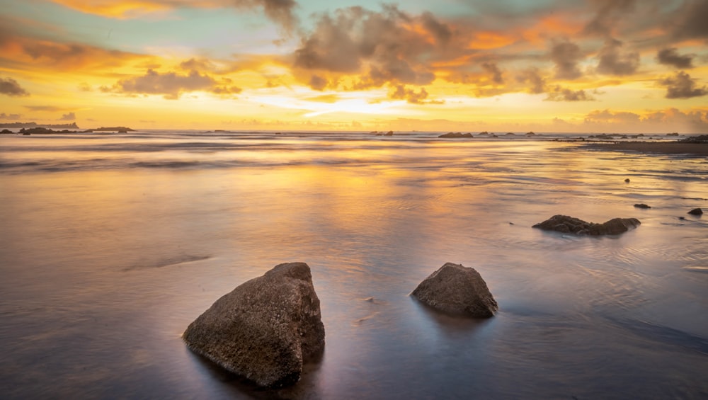 a couple of rocks sitting on top of a sandy beach