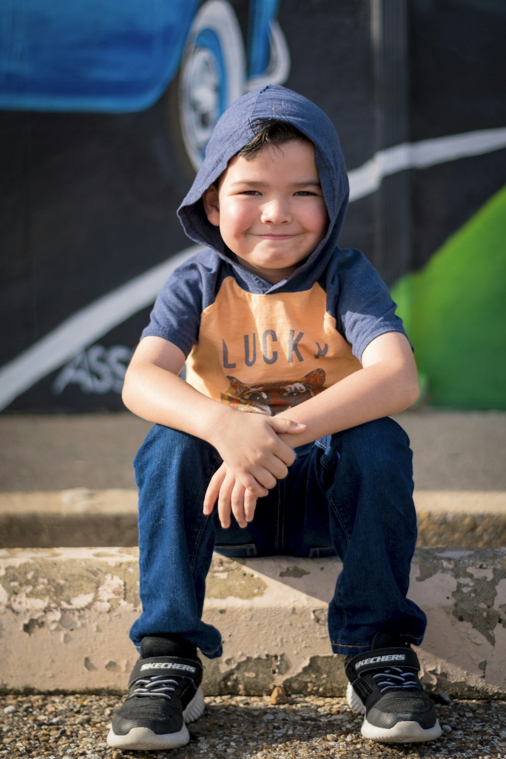 a young boy sitting on a ledge with his hands on his knees